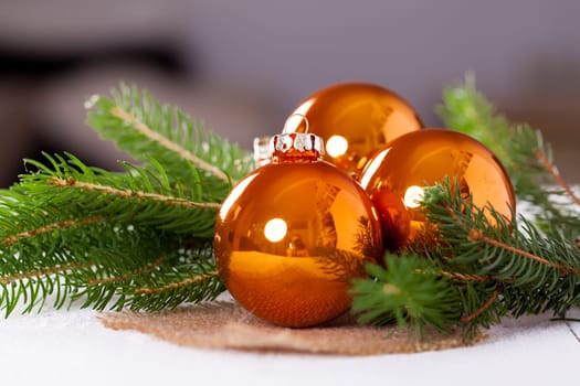 Shiny orange glass balls Christmas balls with green twigs on a jute sack as a close-up