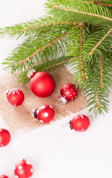 Beautiful red Christmas balls with small white dots with green fir branches on a jute sack