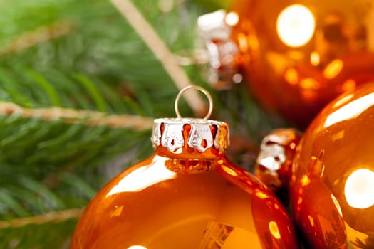 Shiny orange glass balls Christmas balls with green twigs on a jute sack as a close-up