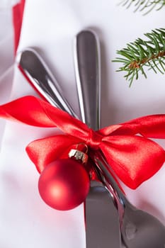 Romantic Christmas table with red balls and red bow with cutlery knife and fork on a napkin
