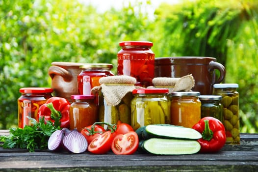 Jars of pickled vegetables in the garden. Marinated food.