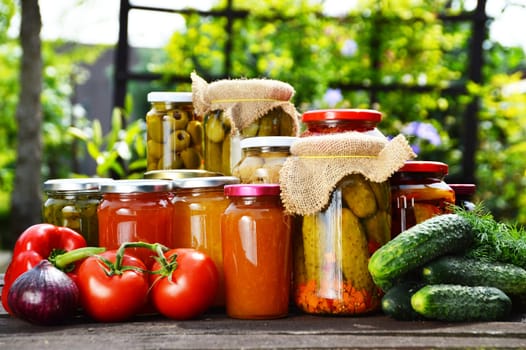 Jars of pickled vegetables in the garden. Marinated food.