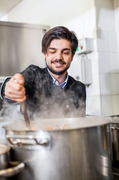 young adult chef in the restaurant kitchen while cooking at the herd preparation