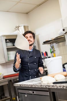 young chef throwing dough pizzadough pizza baker in the restaurant kitchen