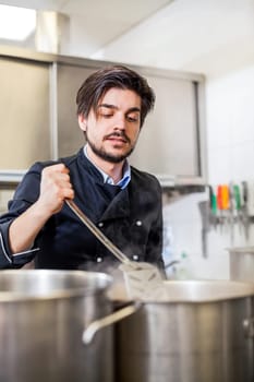 young adult chef in the restaurant kitchen while cooking at the herd preparation