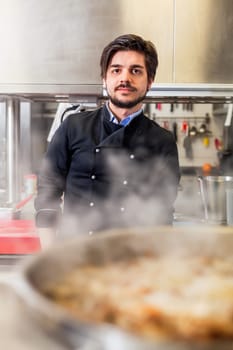 young adult chef in the restaurant kitchen while cooking at the herd preparation