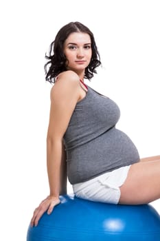 Attractive pregnant woman on a blue gymnastics ball to prepare for the brew