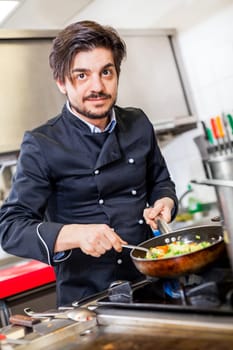 young adult chef in the restaurant kitchen while cooking at the herd preparation