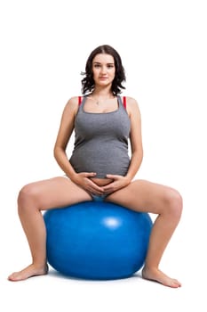Attractive pregnant woman on a blue gymnastics ball to prepare for the brew