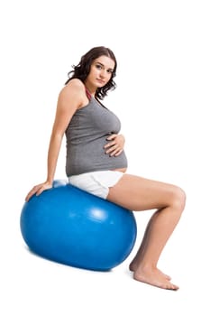 Attractive pregnant woman on a blue gymnastics ball to prepare for the brew