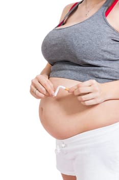 Pregnant woman breaks a cigarette in front of her baby belly isolated against white background