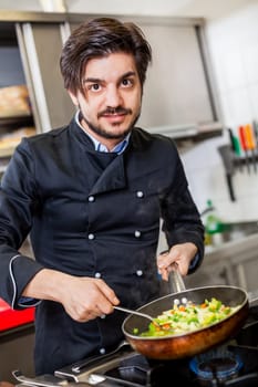 young adult chef in the restaurant kitchen while cooking at the herd preparation