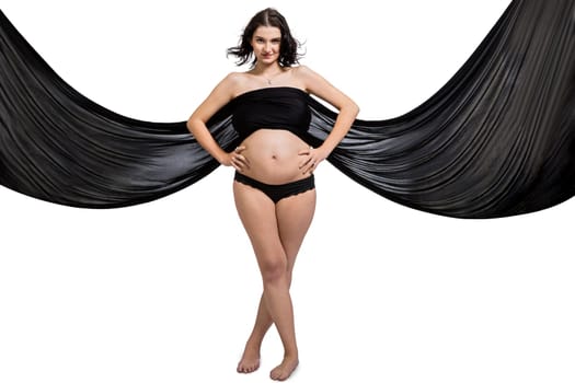 Young attractive pregnant woman wrapped in black fabric insulated against white background