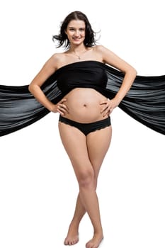 Young attractive pregnant woman wrapped in black fabric insulated against white background