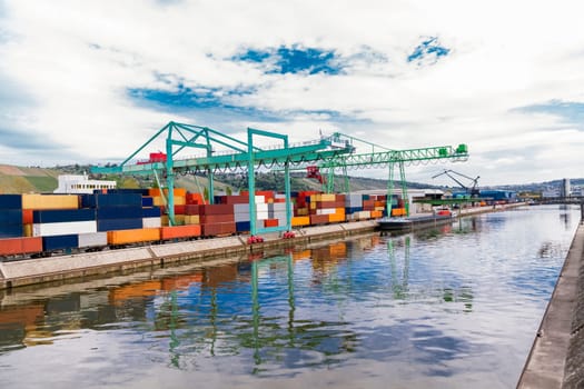 Dock in the port with stacked containers at the dock for import and export cargo with blue sky