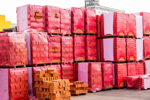Red brick bricks on a pallet packed in a warehouse in the industrial area