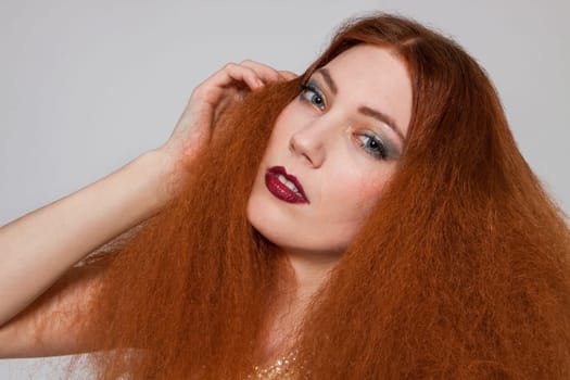 Young attractive pretty woman with long red hair and ripped hairstyle in portrait