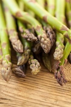 Fresh healthy green asparagus as a close-up on a wooden table in sunlight