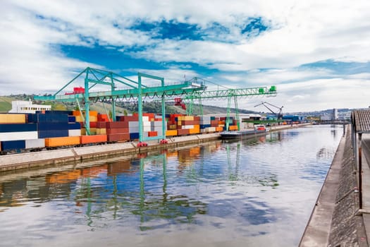 Dock in the port with stacked containers at the dock for import and export cargo with blue sky