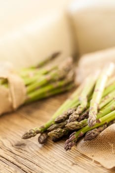Fresh healthy green asparagus as a close-up on a wooden table in sunlight
