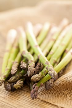 Fresh healthy green asparagus as a close-up on a wooden table in sunlight