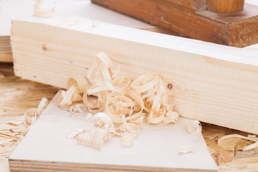 Planing with wood chips in a carpentry shop during woodworking in close-up detail