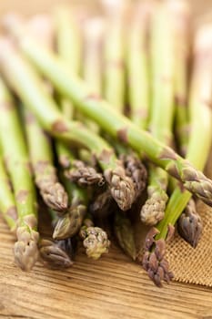 Fresh healthy green asparagus as a close-up on a wooden table in sunlight