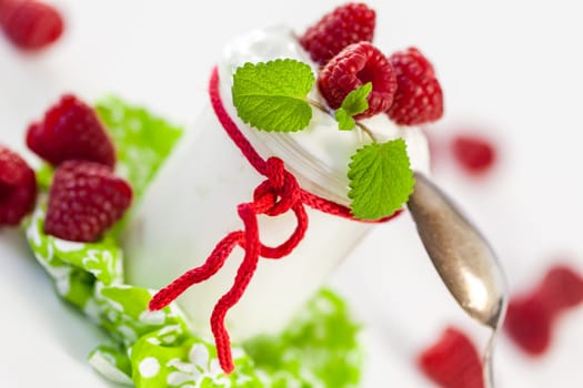 Fresh yoghurt with raspberries in a glass insulated on a white background