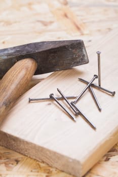 Hammer with nails on a wooden board in a workshop of a do-it-yourselfer