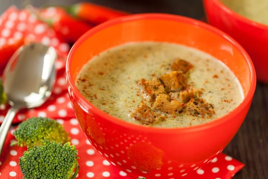 Soup bowl with broccoli soup with fresh pepper and chilli close-up on a wooden table