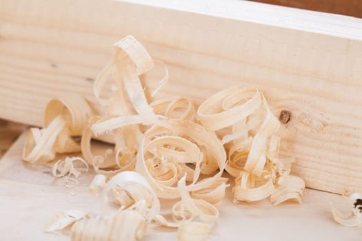 Planing with wood chips in a carpentry shop during woodworking in close-up detail