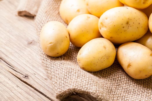 Fresh new potatoes on a jute sack with a green background as a close-up