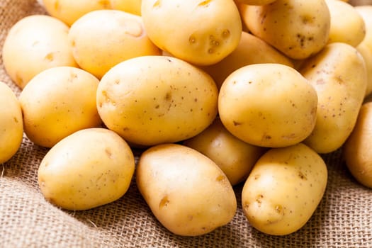 Fresh new potatoes on a jute sack with a green background as a close-up