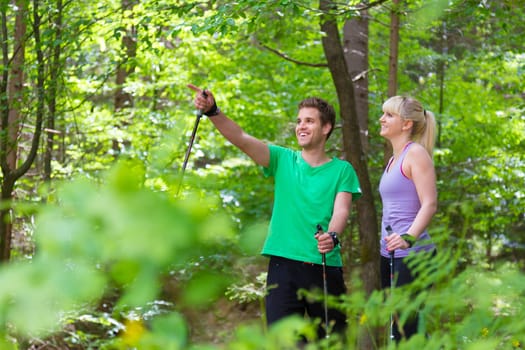 Young spoty active cople with hiking sticks walking in nature. Active lifestyle. Activities and recreation outdoors.