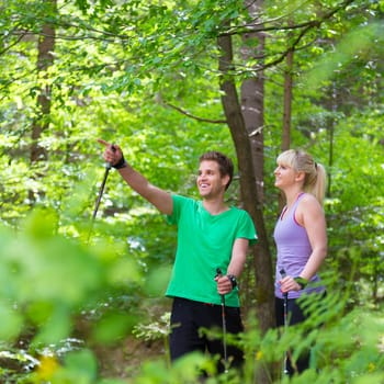 Young spoty active cople with hiking sticks walking in nature. Active lifestyle. Activities and recreation outdoors.