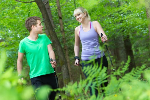 Young spoty active cople with hiking sticks walking in nature. Active lifestyle. Activities and recreation outdoors.