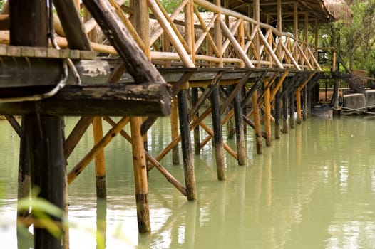 The base of wooden bridge over lake in garden