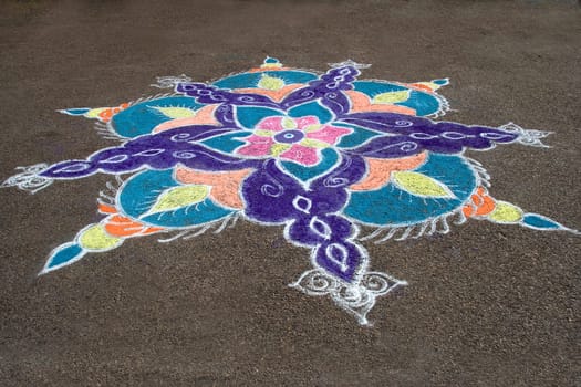 Skillful rangoli handiwork design on floor using colored stone powder