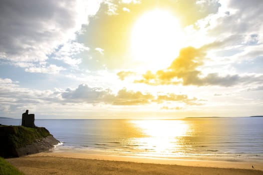 Beautiful yellow sun over the Ballybunion beach and castle in Ireland on a summers day