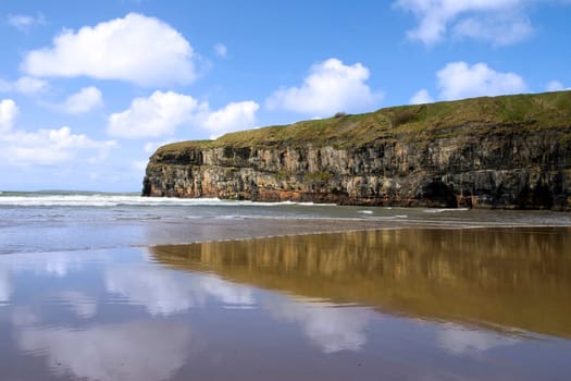 Ballybunion beach and cliffs on the Atlantic coast in Ireland with waves crashing on the cliffs