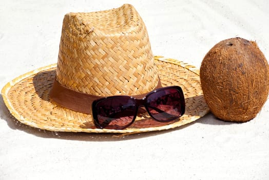 Coconut and straw hat with sunglasses on the beach