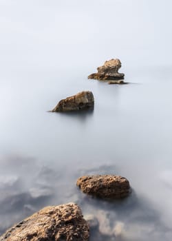 Minimalist fine art view of rocks in the sea taken with long exposure technique