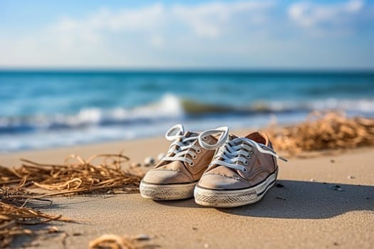 Old worn sneakers on the beach by the blue sea. Summer vacation concept by the sea. Lifestyle travel.