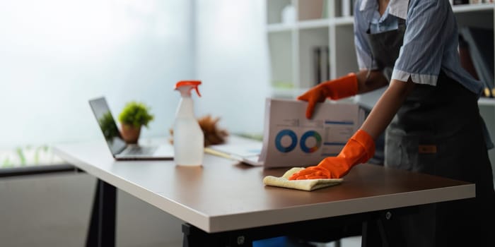 Asian woman cleaning in work room at home. Young woman housekeeper cleaner use a cloth to wipe equipment for working. concept housekeeping housework cleaning.