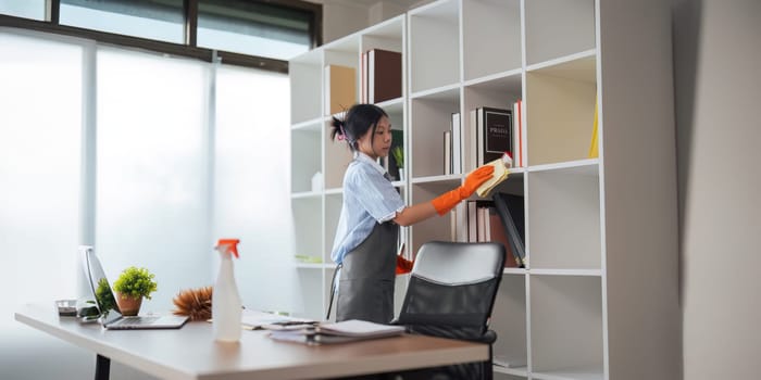 Asian woman cleaning in work room at home. Young woman housekeeper cleaner use a cloth to wipe equipment for working. concept housekeeping housework cleaning.