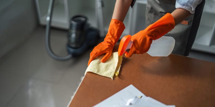 Asian woman cleaning in work room at home. Young woman housekeeper cleaner use a cloth to wipe equipment for working. concept housekeeping housework cleaning.