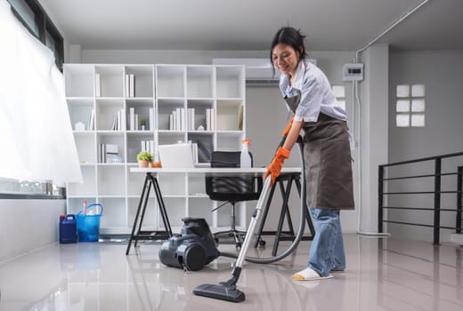 Cleaning in the office Beautiful cleaning lady uses a mop and a vacuum cleaner to clean the floor and get rid of dust. Cleaning concept Housekeeping.