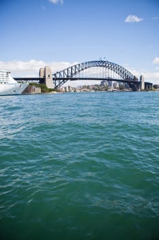 View of Sydney Harbour Bridge in Australia looking of green colored water with front of cruise ship in corner