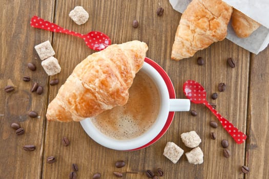 Red cup with coffee and fresh croissants