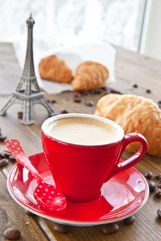 Red cup with coffee and fresh croissants